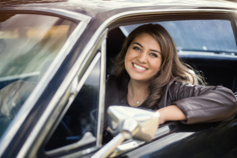 high school senior girl smiling and sitting in a brown car