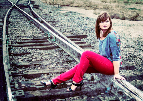 denver senior photography of girl in red pants sitting on train tracks