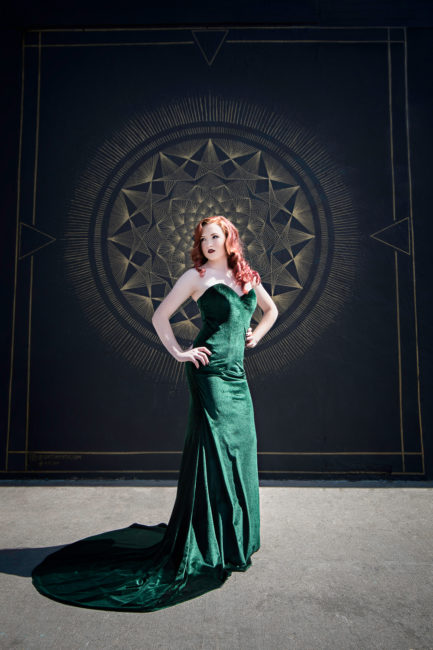 high school senior in denver in a green velvet dress in front of a black and gold wall
