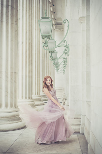 smiling high school senior portrait in a pink dress and white marble setting