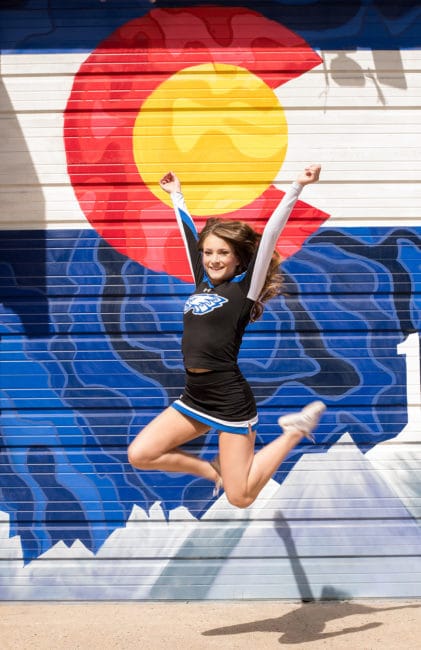 denver cheerleader in front of a colorado themed mural