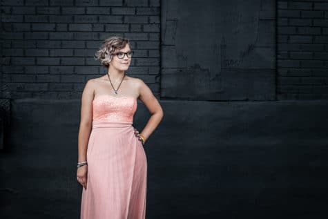 denver senior portrait of girl in a pink dress in front of a black wall