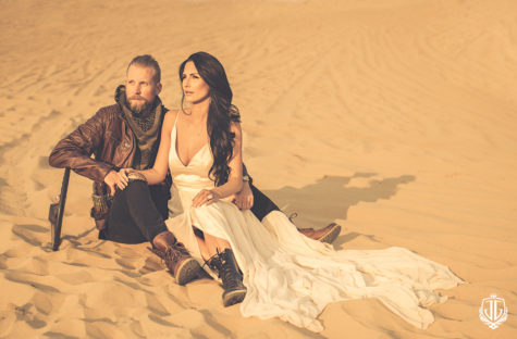 groom in leather jacket and bride sitting in the sand