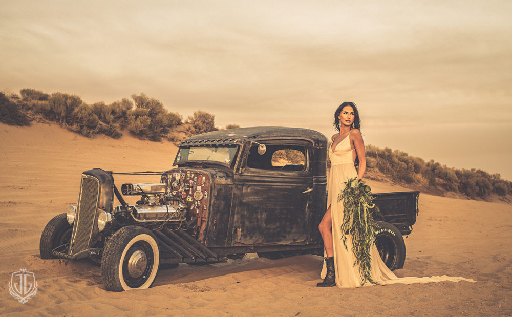 bride in flowy dress standing with hot rod