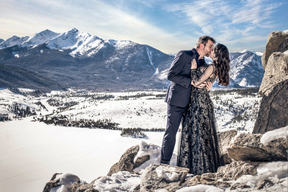 mountain setting with couple in formal attire kissing