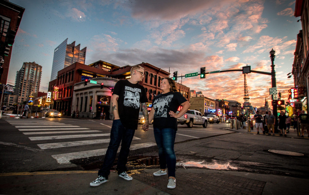 couple in black shirts and jeans holding hands downtown at sunset